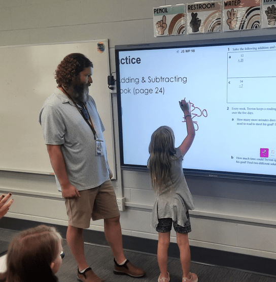 Teacher Apprentice Dyllan Coop teaching Math to students in a classroom.